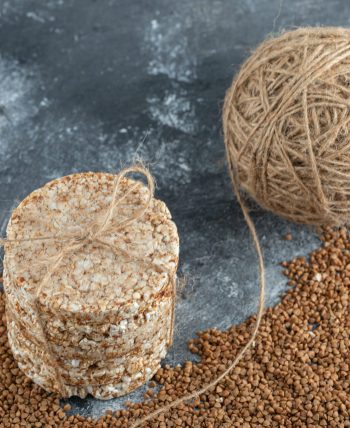 Delicious crispbread, yarn and raw buckwheat on marble background. High quality photo